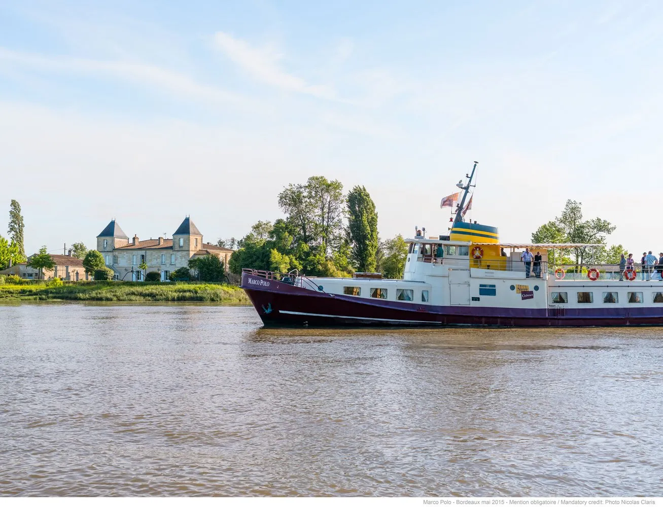 River cruise ship Marco Polo sailing on the Garonne in Bordeaux, with a historic castle visible on the left bank