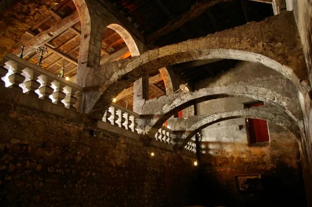 Historic interior of Château du Taillan in Bordeaux featuring stone vaults, curved stairs and illuminated architectural arches