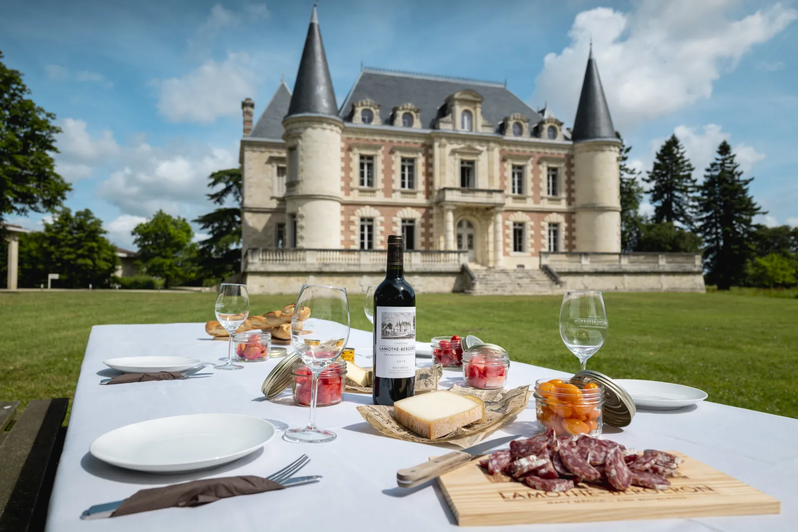 Elegant outdoor dining table with wine, charcuterie and cheese overlooking Château Lamothe Bergeron in Bordeaux