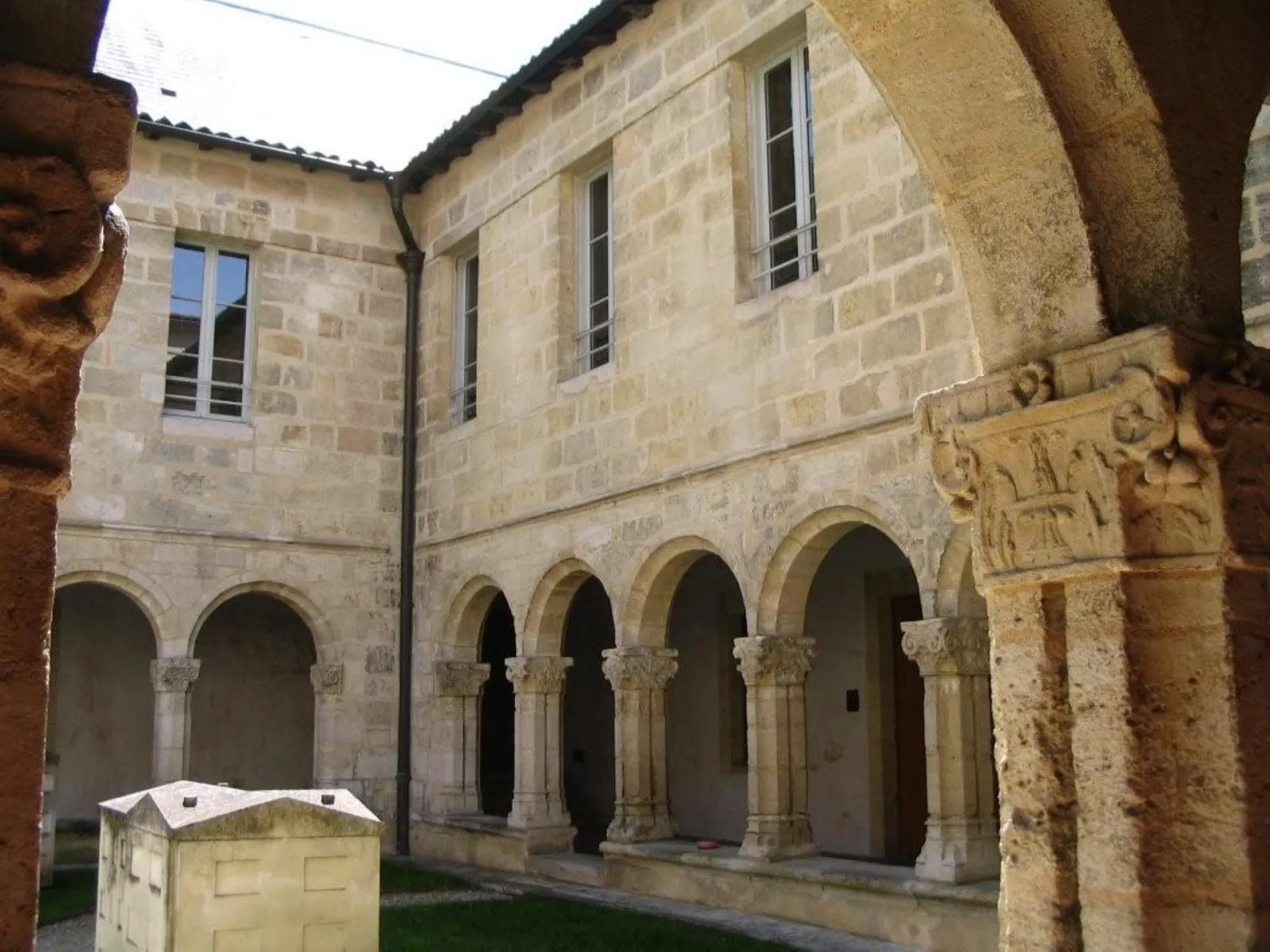 Inner courtyard of the Convent of the Annunciation in Bordeaux featuring Romanesque arcade gallery with carved columns and stone buildings