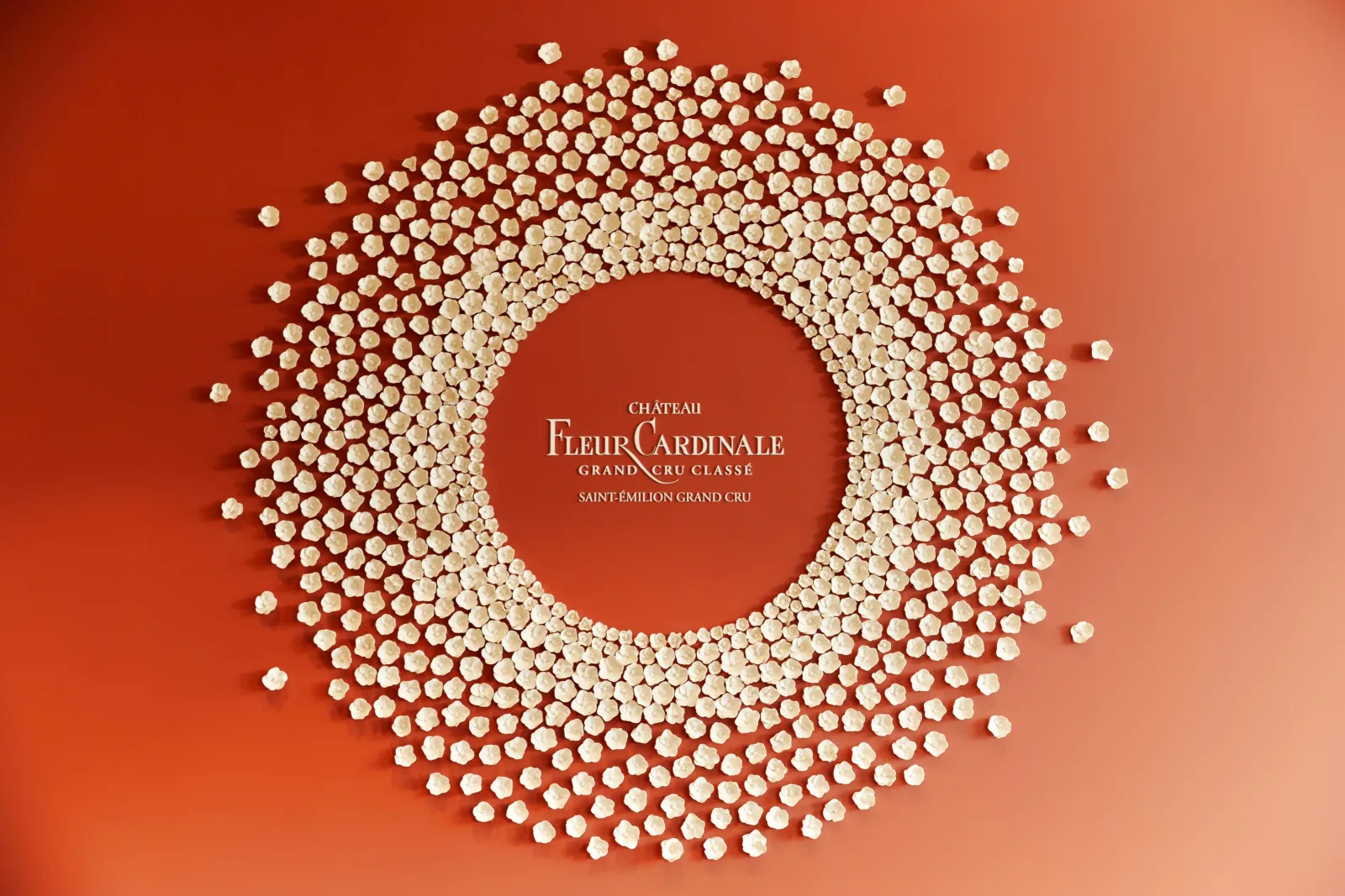 Château Fleur Cardinale logo, a Grand Cru Classé from Saint-Émilion, featuring white and beige pearl-like elements arranged in a circular pattern on a red background.