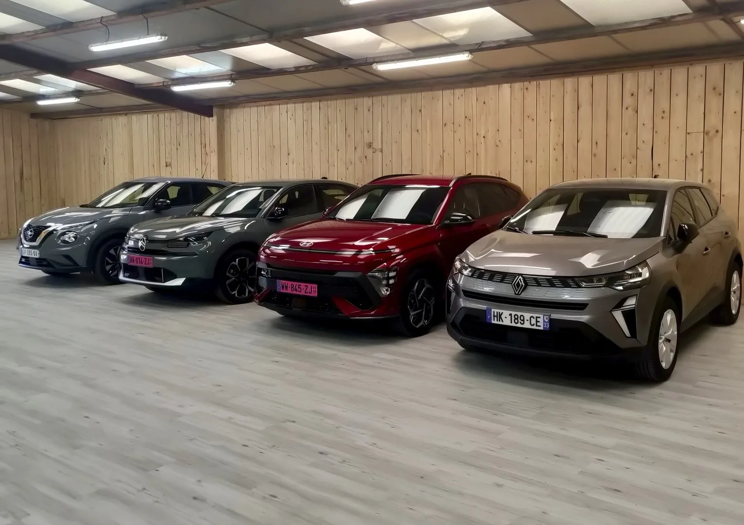 Four electric Renault and Nissan vehicles parked in an underground garage in Bordeaux, featuring a gray Nissan Qashqai, two black models, a red Renault 5, and a beige Renault 5.