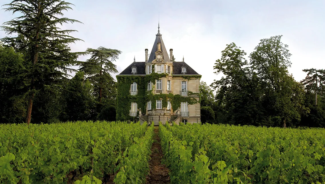 Château les Carmes Haut-Brion in Bordeaux, a 19th-century mansion with mansard roof surrounded by vineyards and mature trees