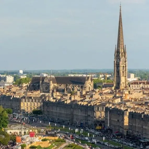 Aerial view of Bordeaux showcasing the Saint-Michel Spire dominating the historic city center with its stone buildings and mansard roofs.
