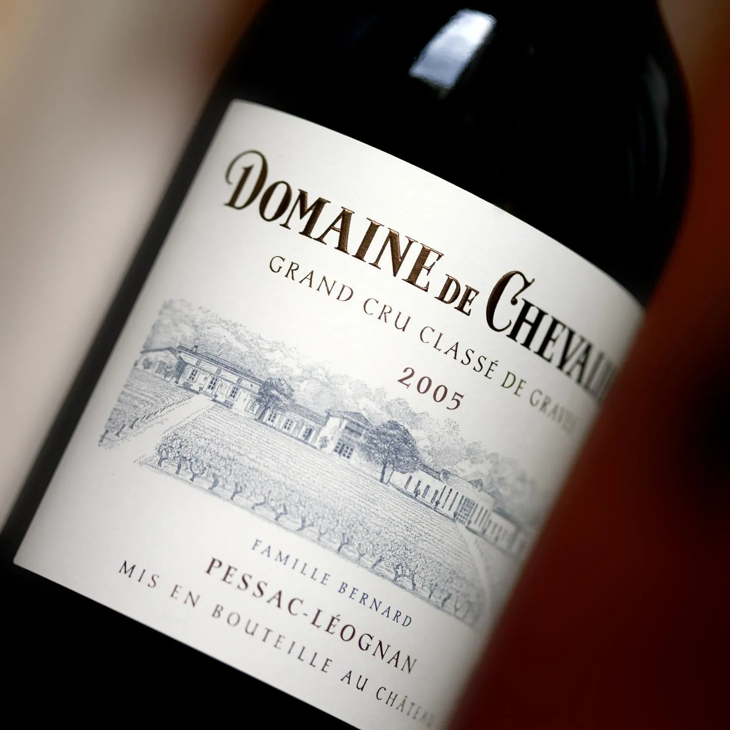 Bottle of Domaine de Chevalier red wine, Grand Cru Classé de Graves 2005, Pessac-Léognan, Bordeaux, with white label featuring a château illustration.