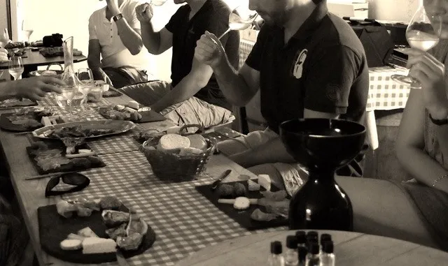 Group of people gathered around a table with dishes and glasses during a convivial meal in black and white