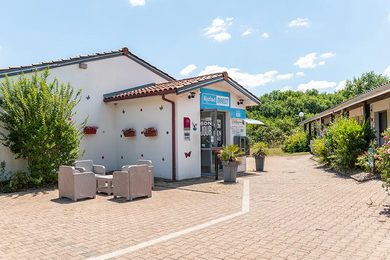Kyriad Direct Bordeaux South Cestas hotel entrance with reception area, lounge seating, and landscaped grounds under clear skies