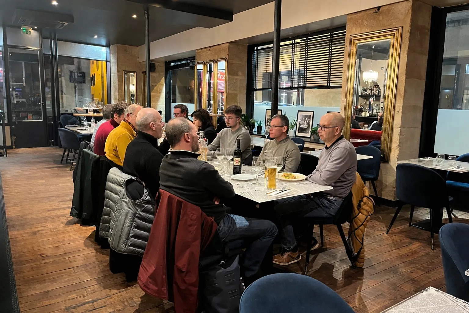 Group of people gathered around a table in a modern restaurant in Bordeaux, sharing a meal and conversation.