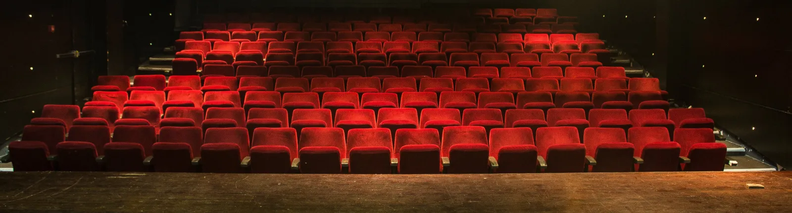 Empty red theater seats arranged in rows inside the Molière Theater in Bordeaux, illuminated and tiered.