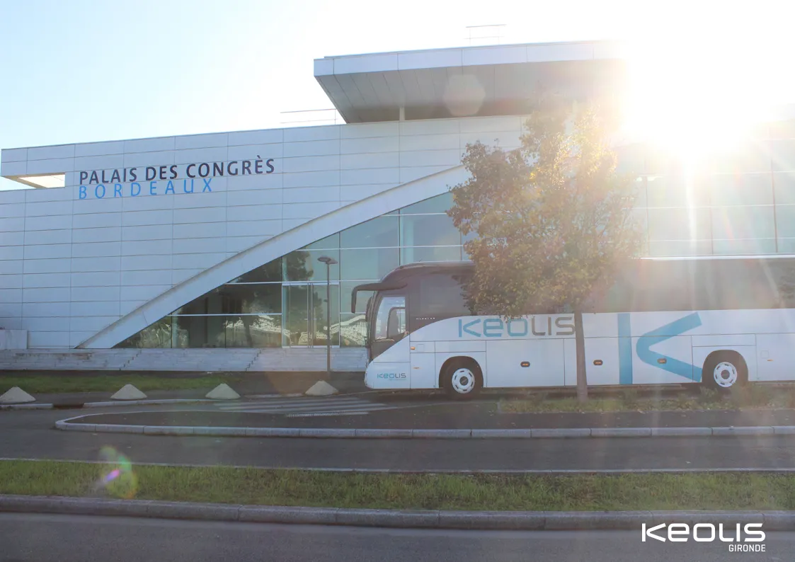 A white Keolis Gironde coach bus in front of the Palais des Congrès in Bordeaux at sunset