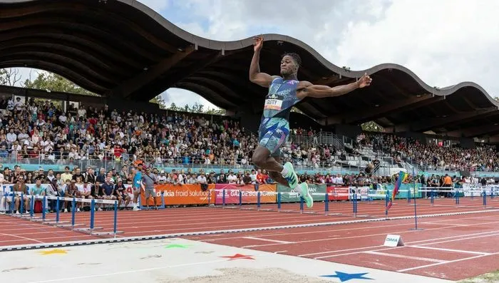 Athlete competing in the hurdles event at the Décastar international athletics competition in Bordeaux, with a crowd-filled stadium in the background.