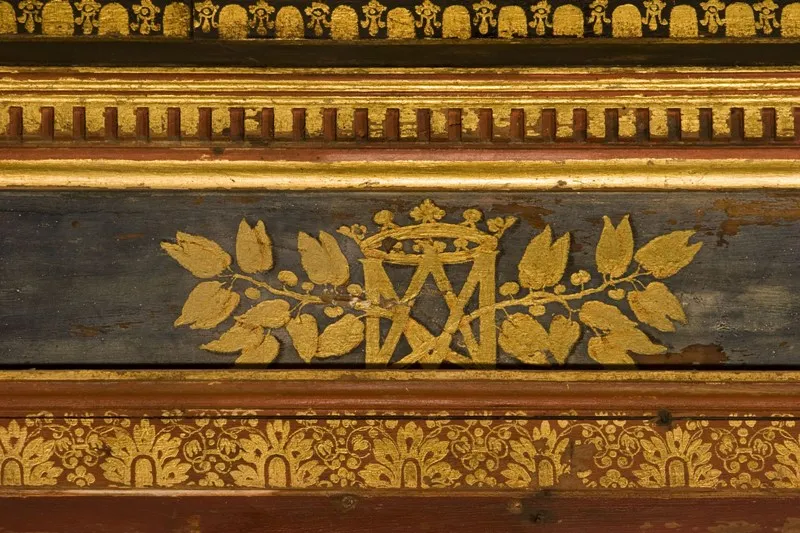 Gilded wood paneling detail from Cadillac Castle in Bordeaux, featuring geometric and floral gold leaf patterns on a dark background