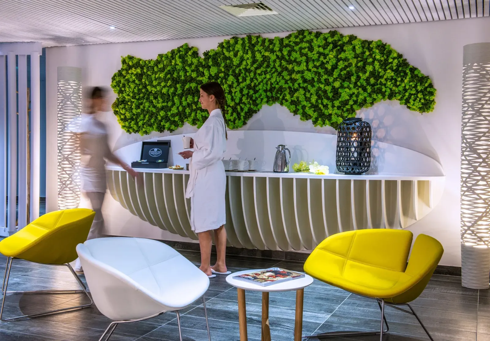 Modern reception area of Spa Dock G6 in Bordeaux featuring a green living wall, contemporary desk, and yellow lounge chairs