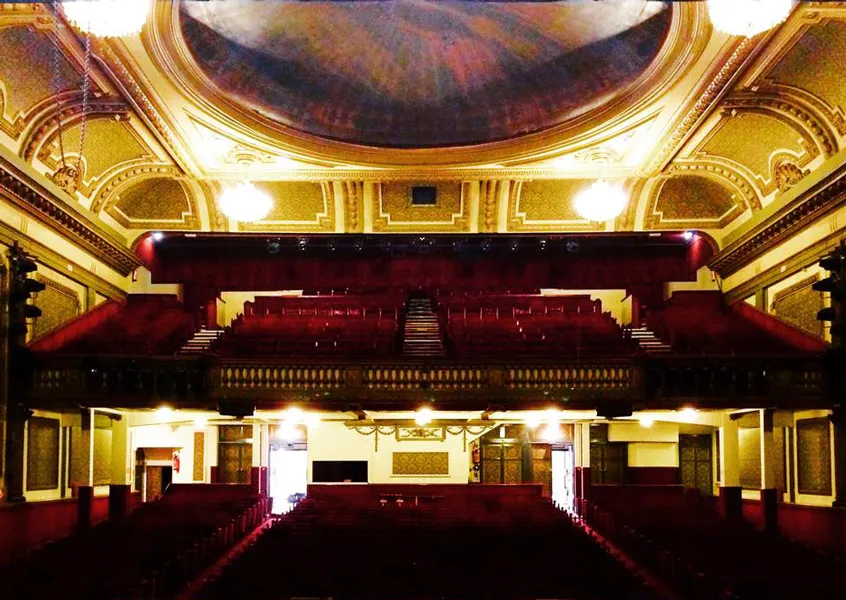 Interior of Bordeaux's Théâtre Fémina featuring a gilded dome ceiling, red velvet balconies, seating area, and Belle Époque architectural details.