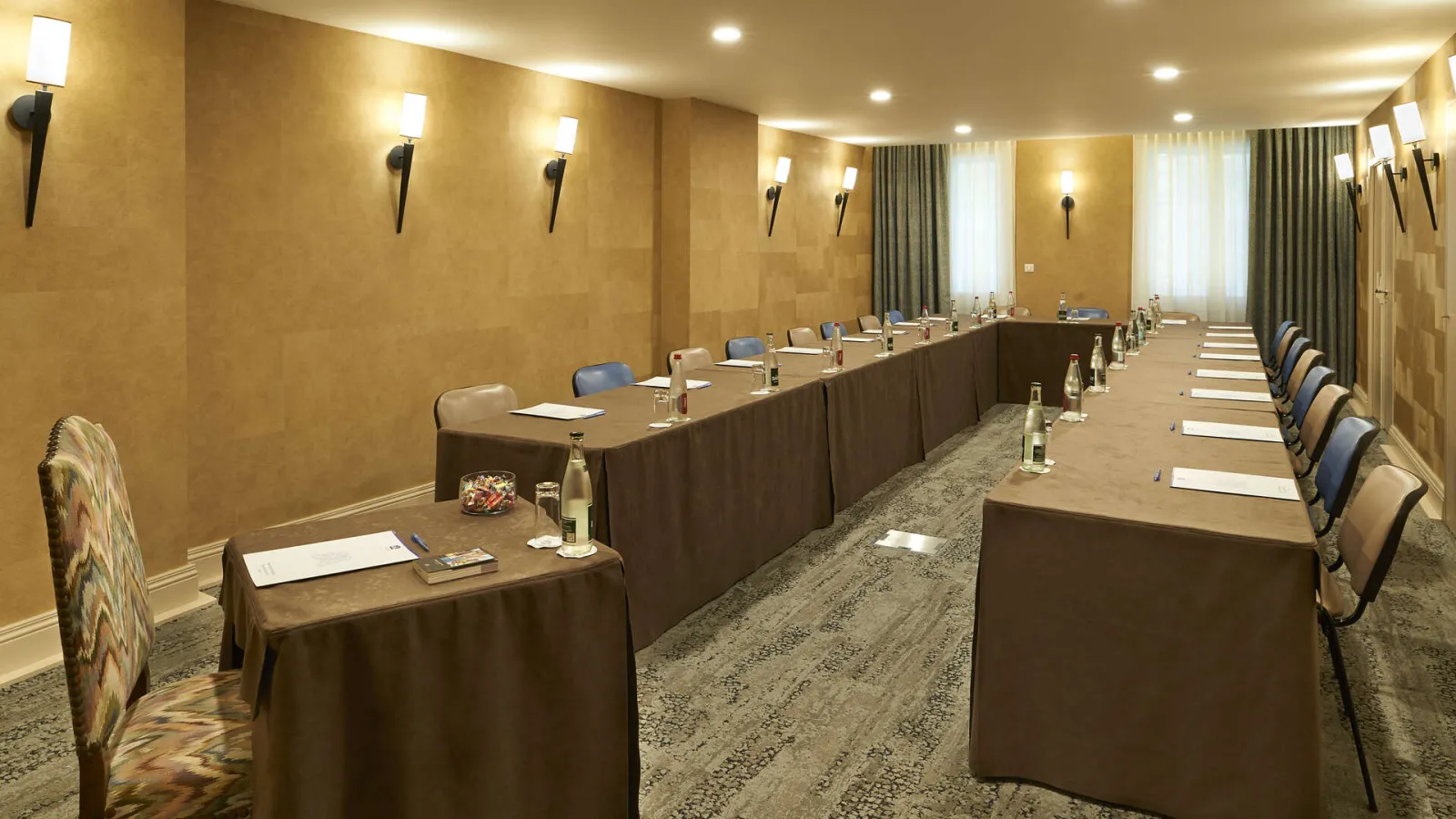 Elegant conference room with U-shaped table setup, blue chairs, golden walls, wall sconces and green curtains at Best Western Premier Hôtel Bayonne Etche Ona in Bordeaux