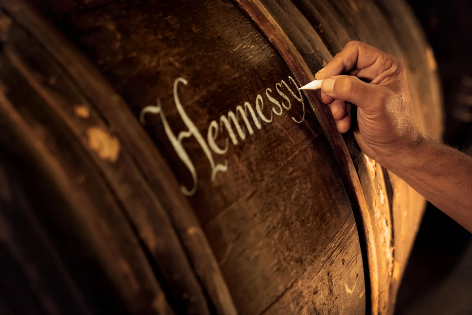 Hand engraving the Hennessy name on a cognac barrel at Hennessy House in Bordeaux