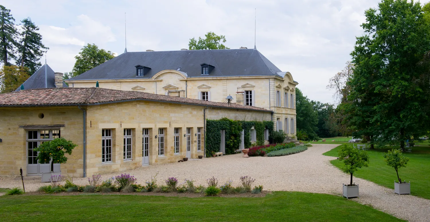 The Table de Siaurac in Bordeaux: stone building with slate mansard roof, adjoining orangery, gravel courtyard and landscaped gardens.