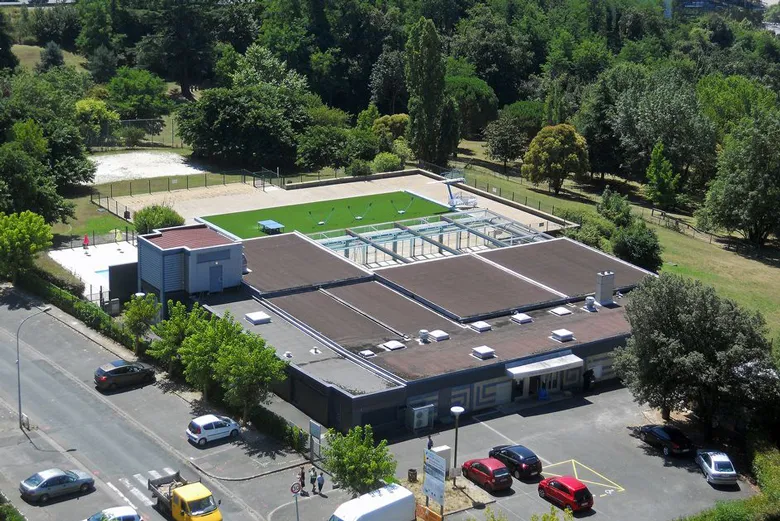 Aerial view of Lormont municipal swimming pool in Bordeaux featuring pools, facilities, parking lot and surrounding green areas