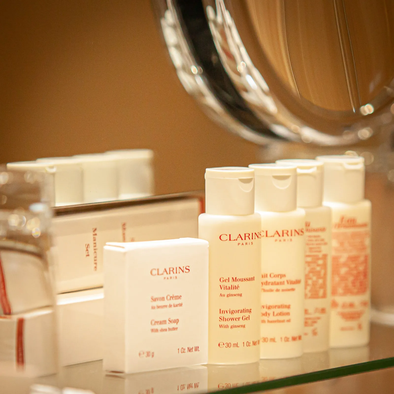 Clarins skincare products displayed on a bathroom shelf, featuring cream soap and invigorating shower gel with ginseng, at the Churchill Hotel in Bordeaux.