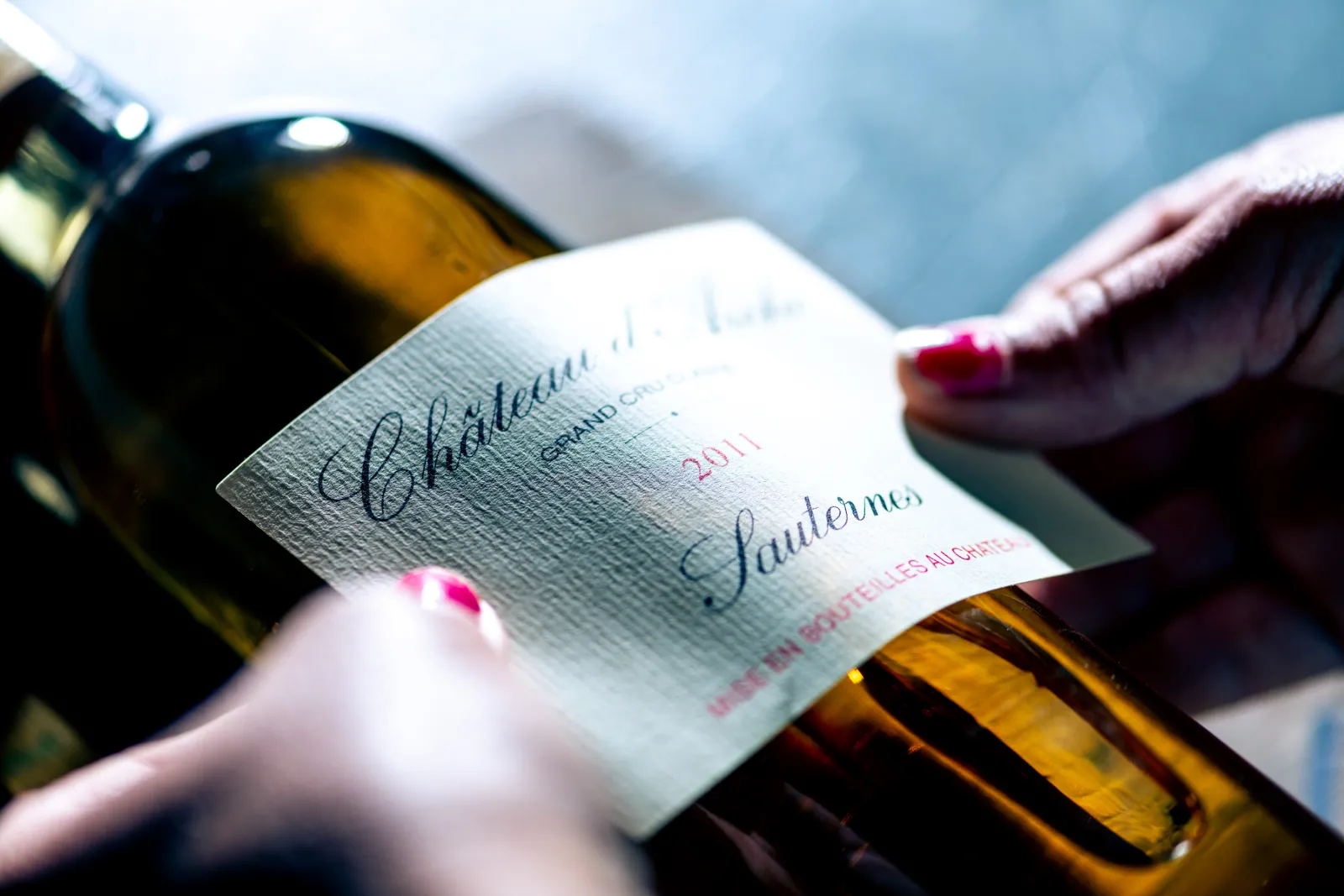 Bottle of Château d'Arche white wine from Sauternes vintage 2011 held in hand with visible label