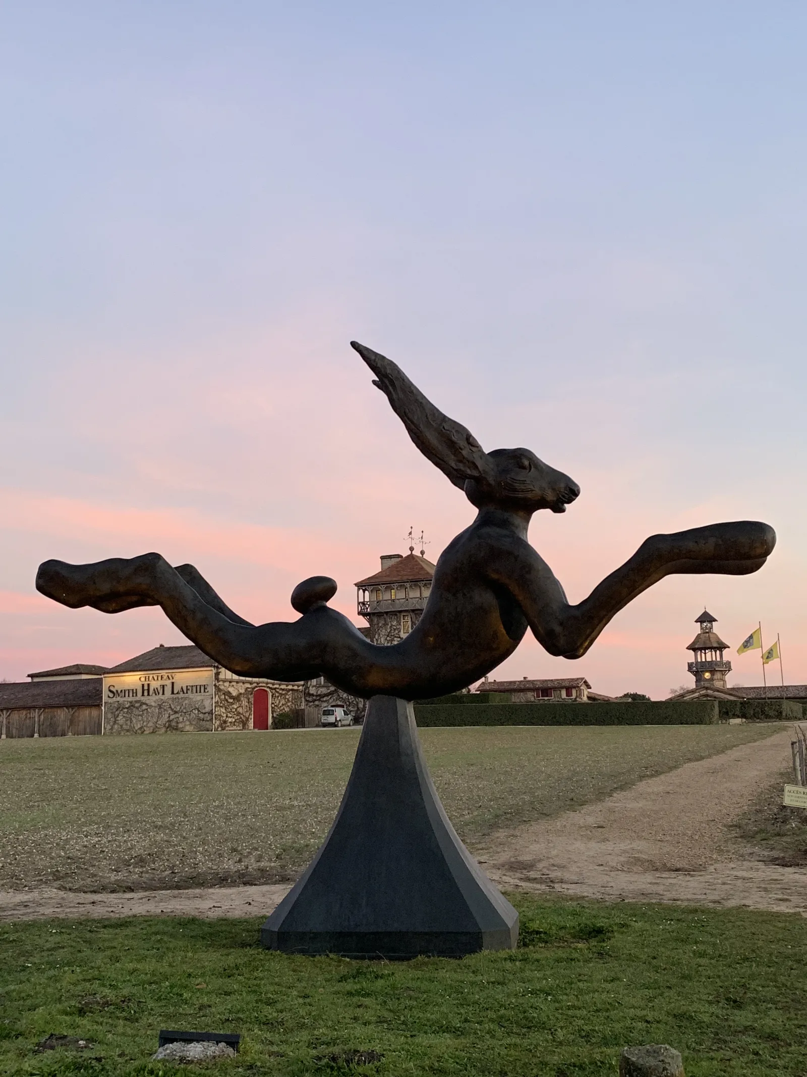 Abstract bronze sculpture of a dynamic reclining figure at Château Smith Haut Lafitte in Bordeaux, at sunset.