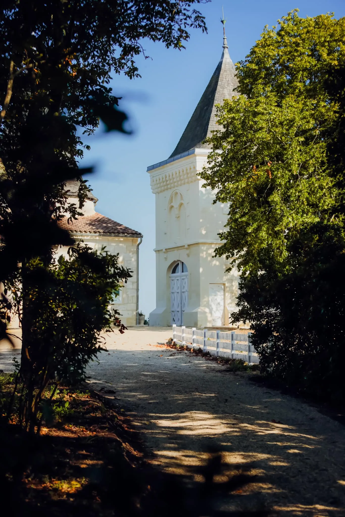 White church with pointed black steeple surrounded by lush green foliage in Bordeaux