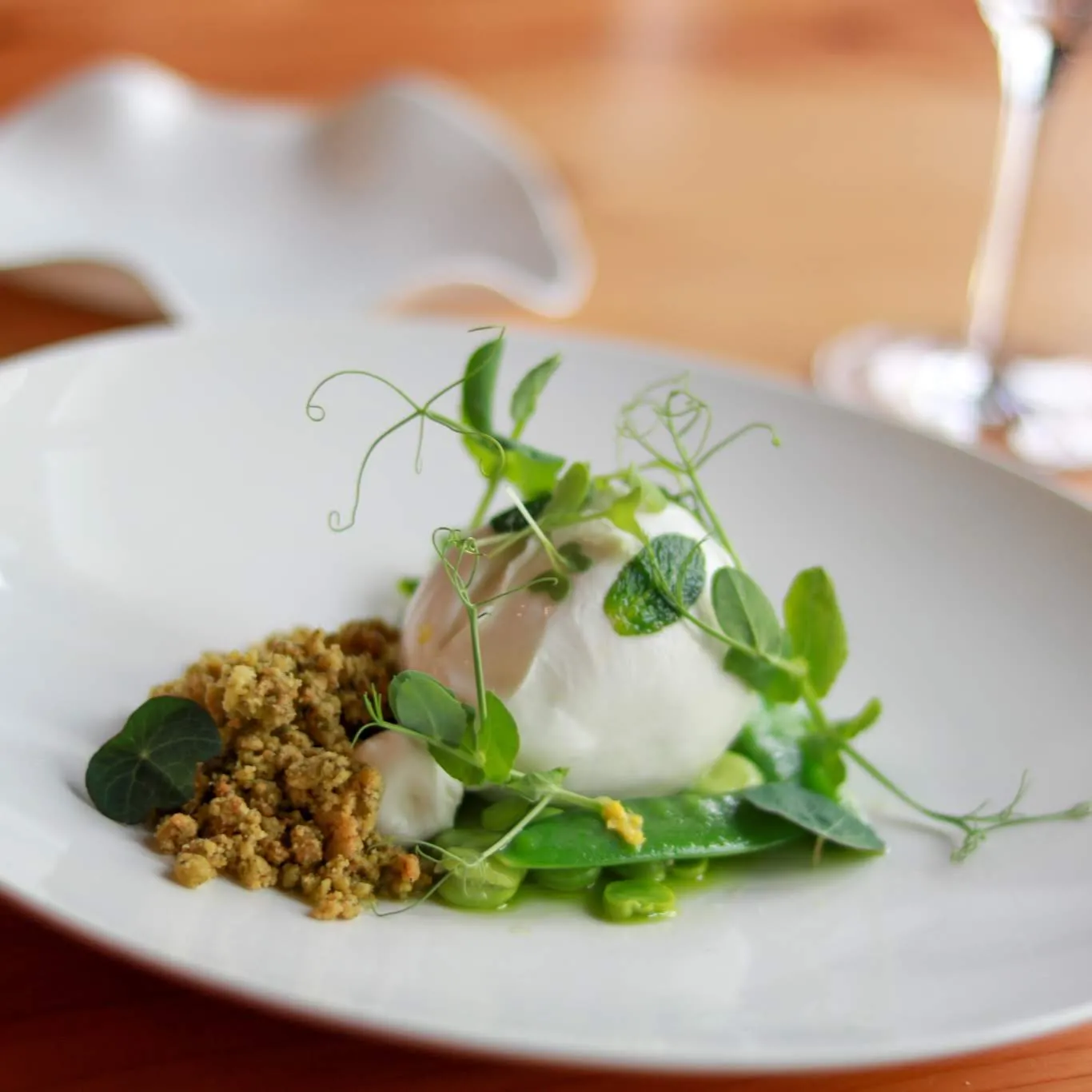 Gourmet plated dish featuring a quenelle of fresh cheese surrounded by sugar snap peas, delicate microgreens and toasted breadcrumb crumble, served at Le Loup restaurant in Bordeaux.