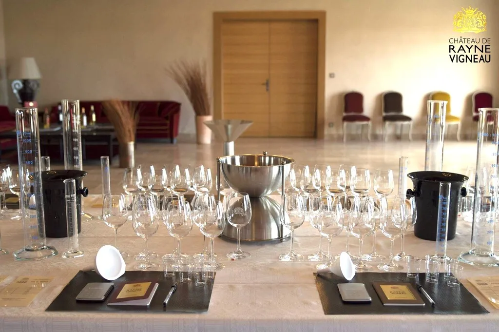 Tasting room at Château de Rayne Vigneau in Bordeaux featuring an elegantly set table with wine glasses, decanters, and place settings