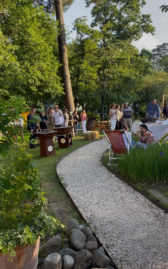 Lush park with winding gravel pathway, visitors scattered among tall trees, artistic installations and seating areas during a public event in Bordeaux.