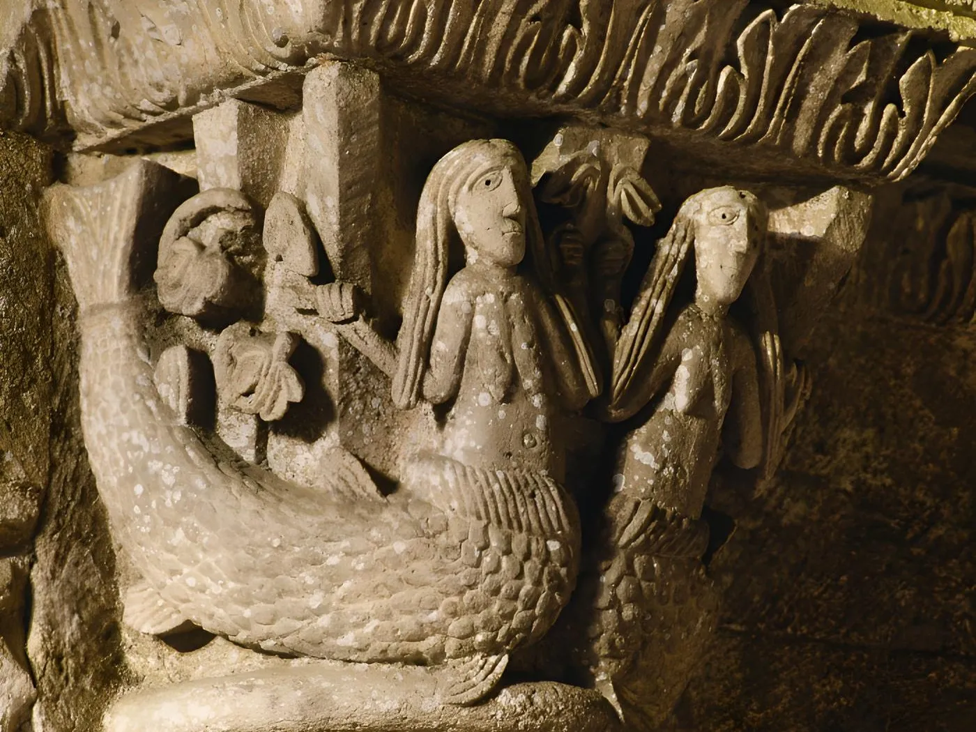 Carved capital from La Sauve-Majeure Abbey depicting a mermaid or sea creature with two figures, Romanesque architectural detail from the 12th century