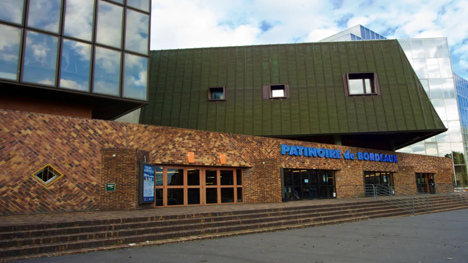 Bordeaux Ice Rink entrance featuring red brick facade, modern green roof, and blue signage