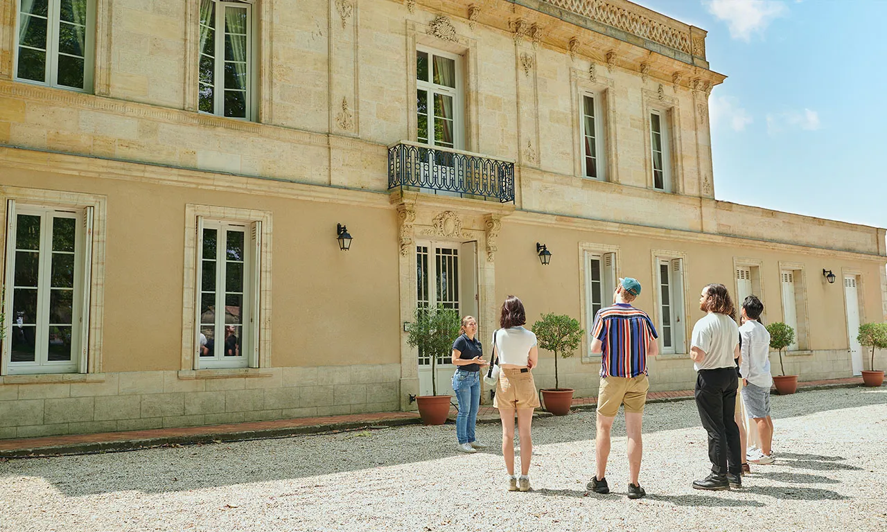 Visitors standing in the courtyard of Château Haut Breton Larigaudière in Bordeaux, with the classical stone facade and symmetrical windows
