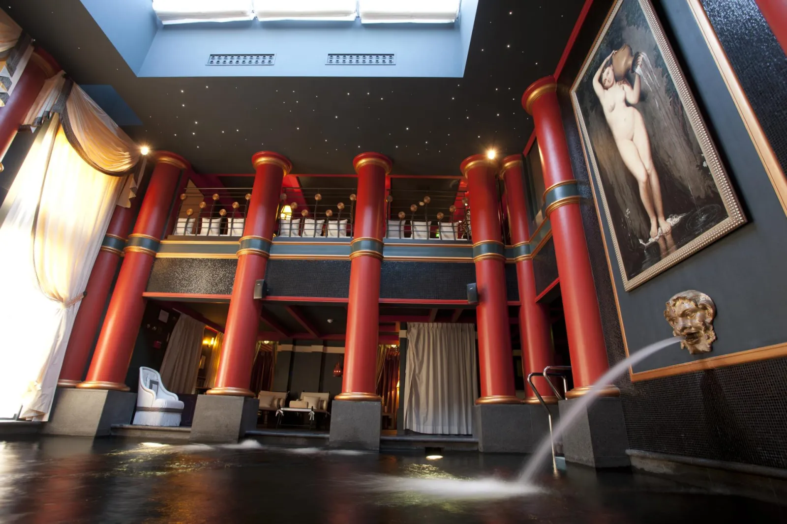 Elegant interior of Bordeaux's Guerlain spa featuring illuminated red columns, upper balcony and luxurious decor