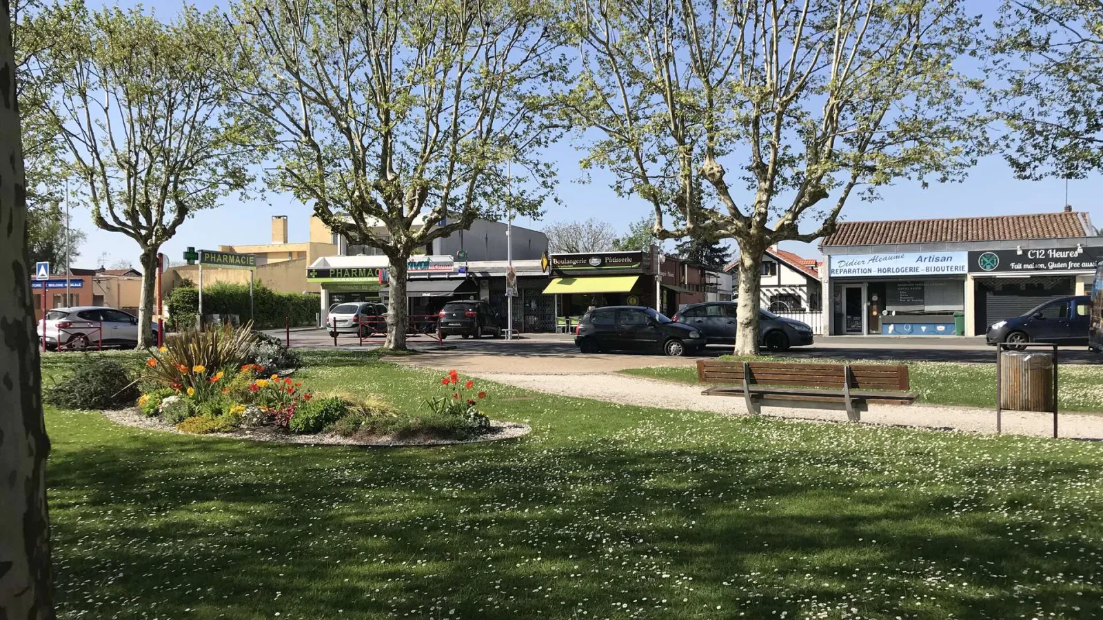 Public square in the Cité Frugès at Pessac featuring green spaces, benches, local shops and typical modernist residential architecture.