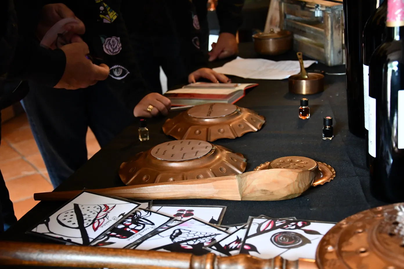 Participants in a wine-themed escape game examining copper objects and illustrated documents during an oenology workshop in Saint-Emilion.