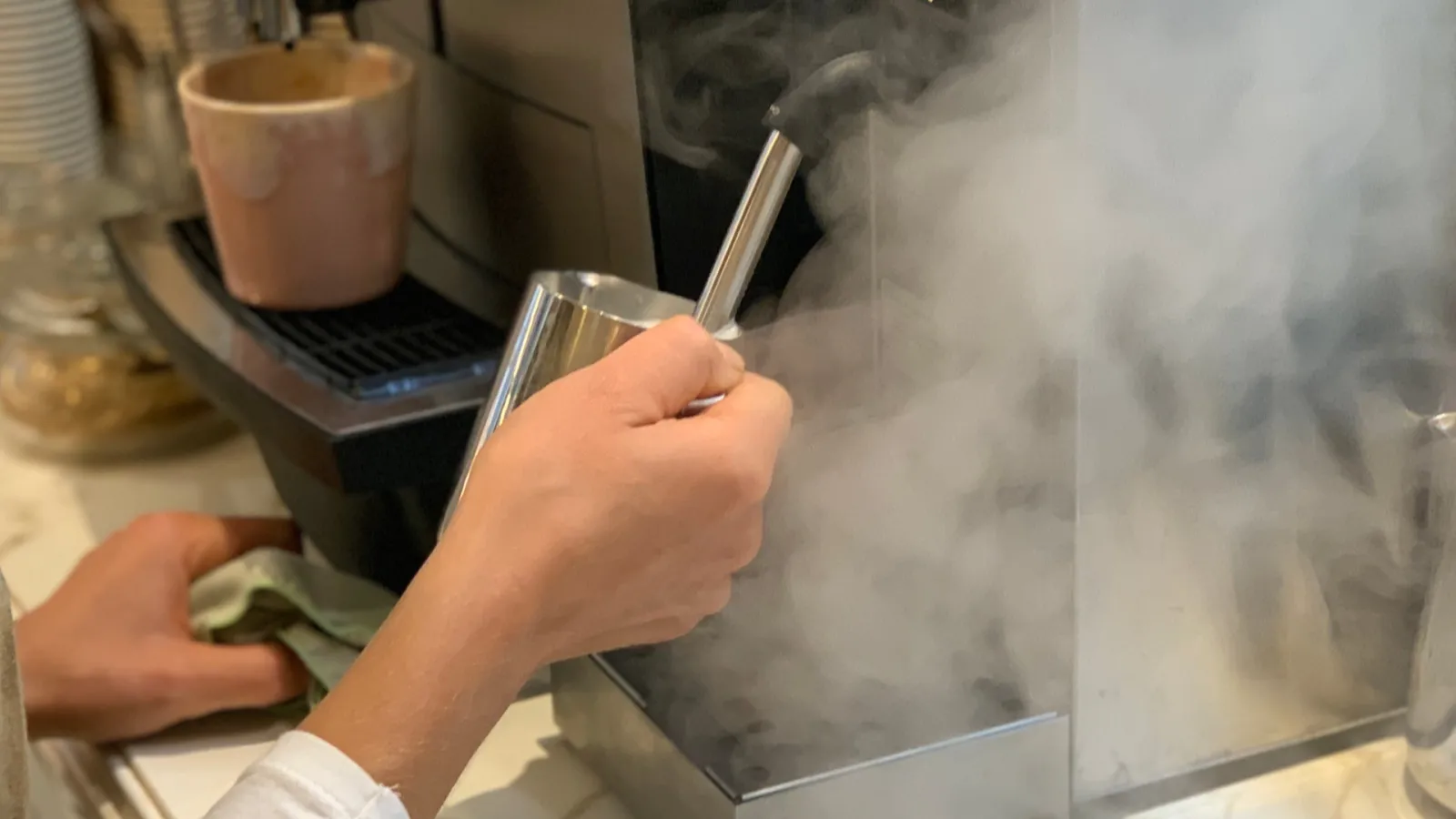 Hand holding a glass filled with dry ice fog vapor from a fog machine, with a pink cardboard cup in the background at a Cassonade establishment in Bordeaux