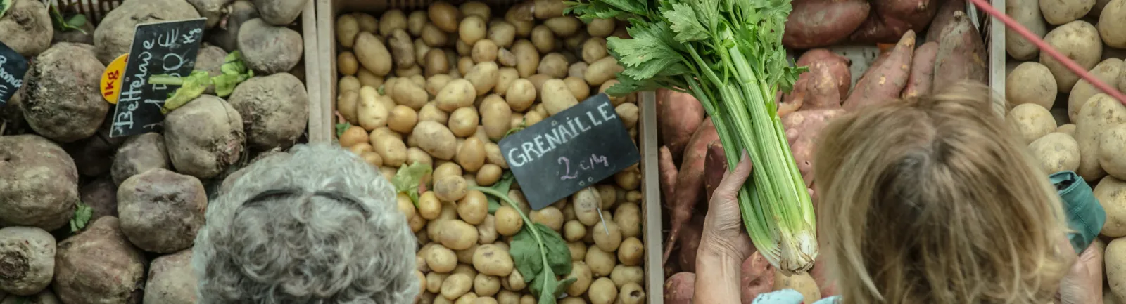 Market stall at Saint-Augustin Market in Bordeaux displaying fresh vegetables including beets, potatoes, small grenaille potatoes, and parsley with handwritten price signs.