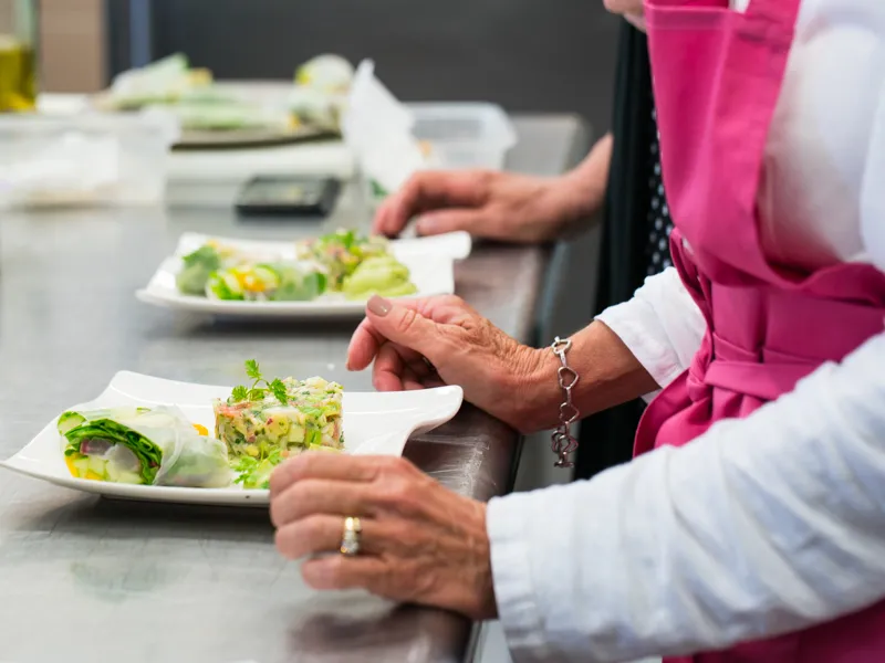 Two women in chef's attire presenting plated gourmet dishes during a cooking workshop at Château Kirwan in Bordeaux