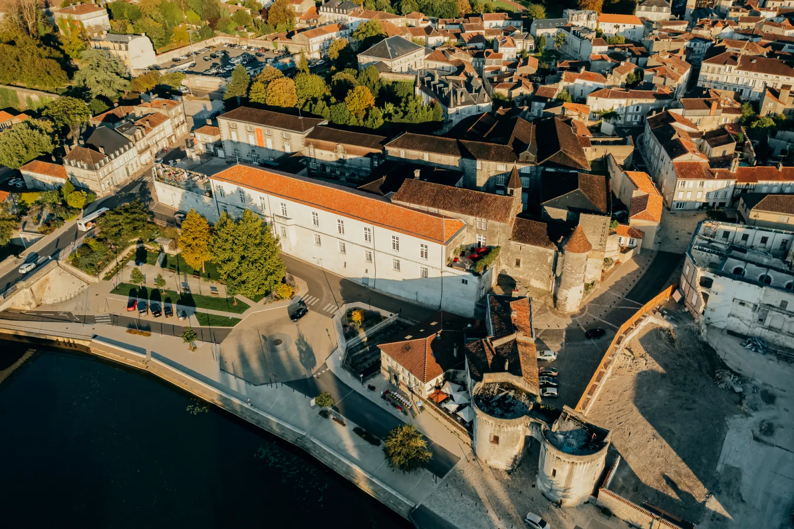 Aerial view of Cognac Castle in Bordeaux showing fortified towers along the waterfront, surrounded by historic buildings and the medieval city