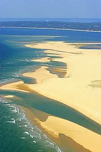 Aerial view of Arcachon Basin featuring golden sandbars, turquoise waters, and winding channels along the Atlantic coast