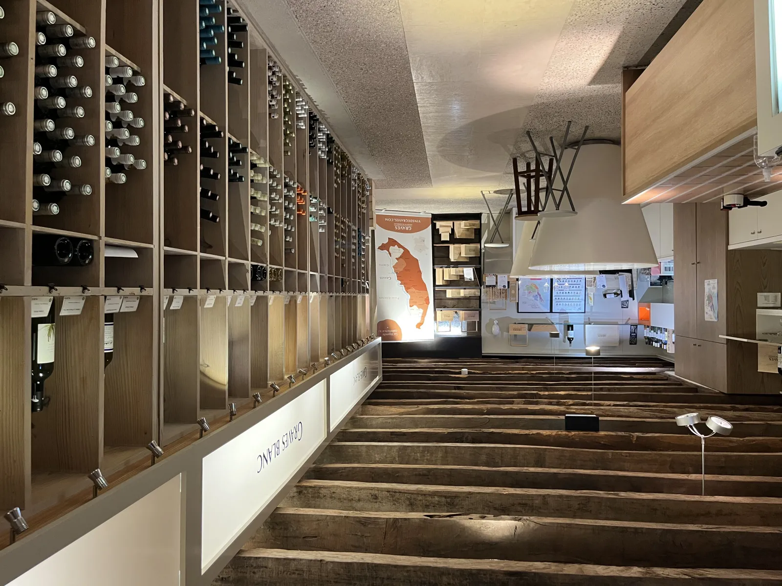 Interior of the Maison des Vins de Graves in Bordeaux featuring wine tasting lockers, a service counter, and a promotional poster showcasing regional wines.