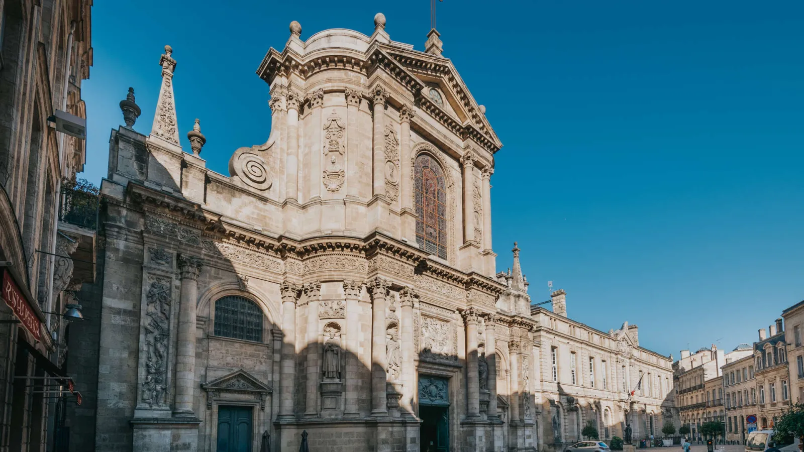 Ornate baroque facade of Notre-Dame Church in Bordeaux, featuring a domed roof and intricate stone carvings, overlooking the Mably square.
