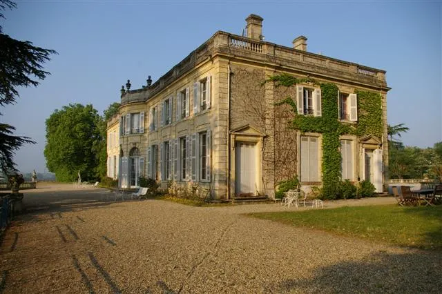 Façade of Château du Taillan in Bordeaux, a classical stone manor with climbing ivy, gravel courtyard and surrounding trees.