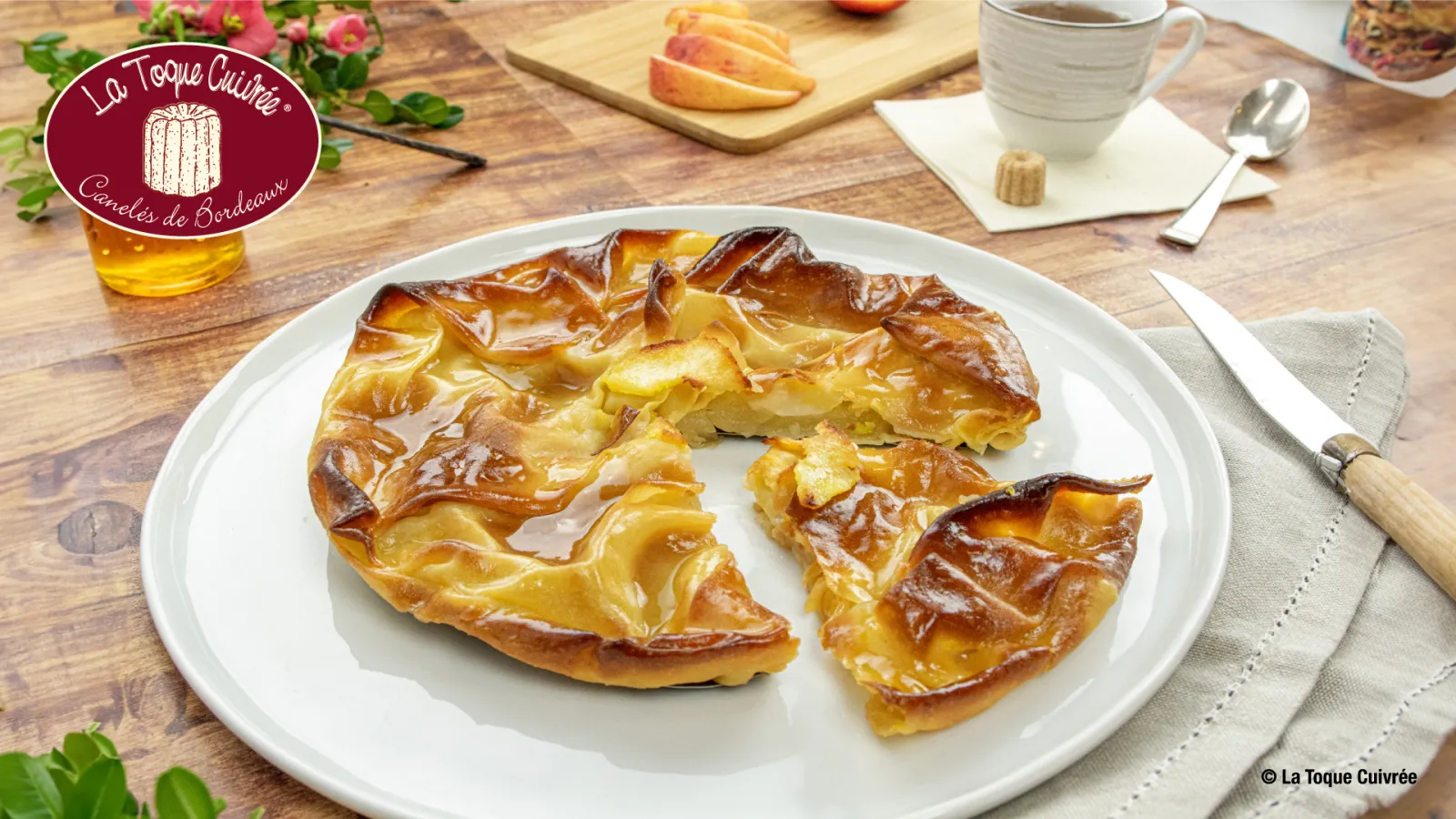 Golden caramelized Tarte Tatin served on a white plate at La Toque Cuivrée in Bordeaux, with coffee and fresh fruit in the background.