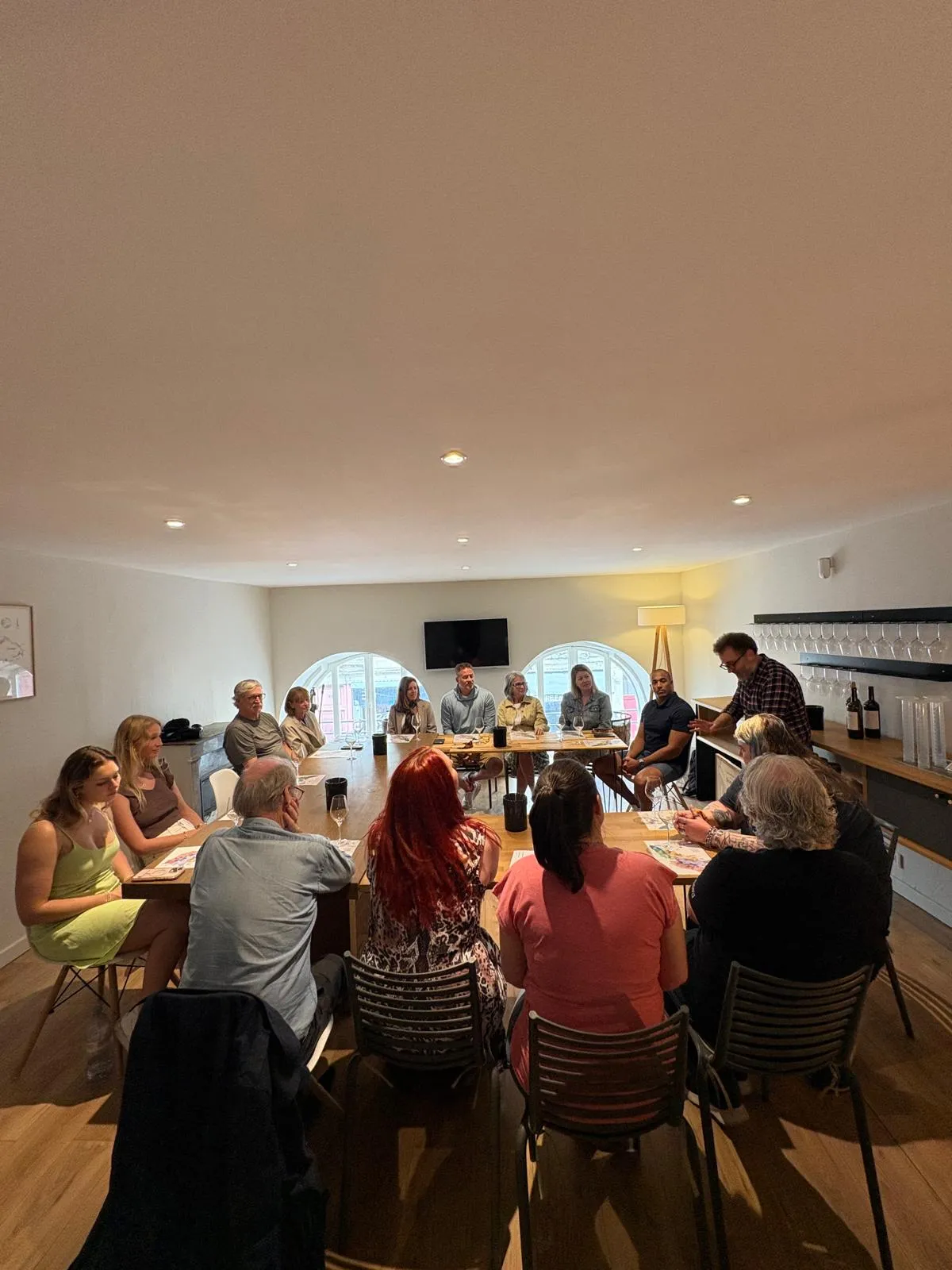 Group of people gathered around a table in a modern room in Bordeaux, participating in a meeting or social gathering.