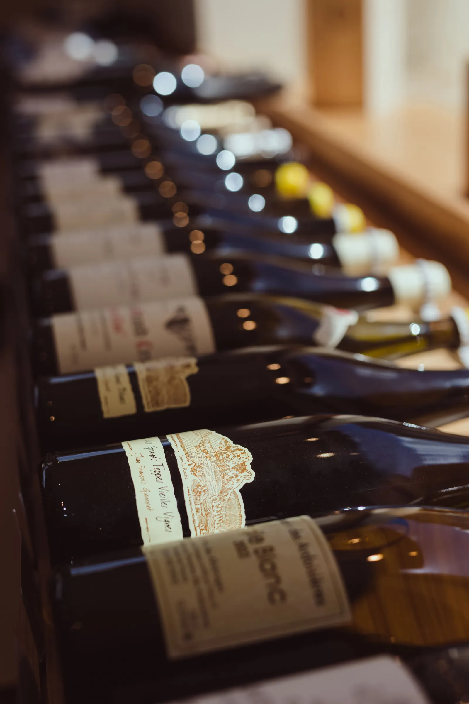 Row of Bordeaux wine bottles arranged with visible labels in a cellar with soft lighting.