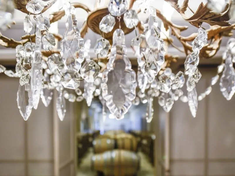 Close-up of a crystal chandelier with sparkling glass pendants hanging from a gilded frame in a bedroom at Château Beauregard in Bordeaux.