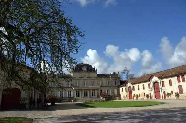 Interior courtyard of Château Giscours in Bordeaux featuring stone buildings, green lawn, and classical 18th-century architecture