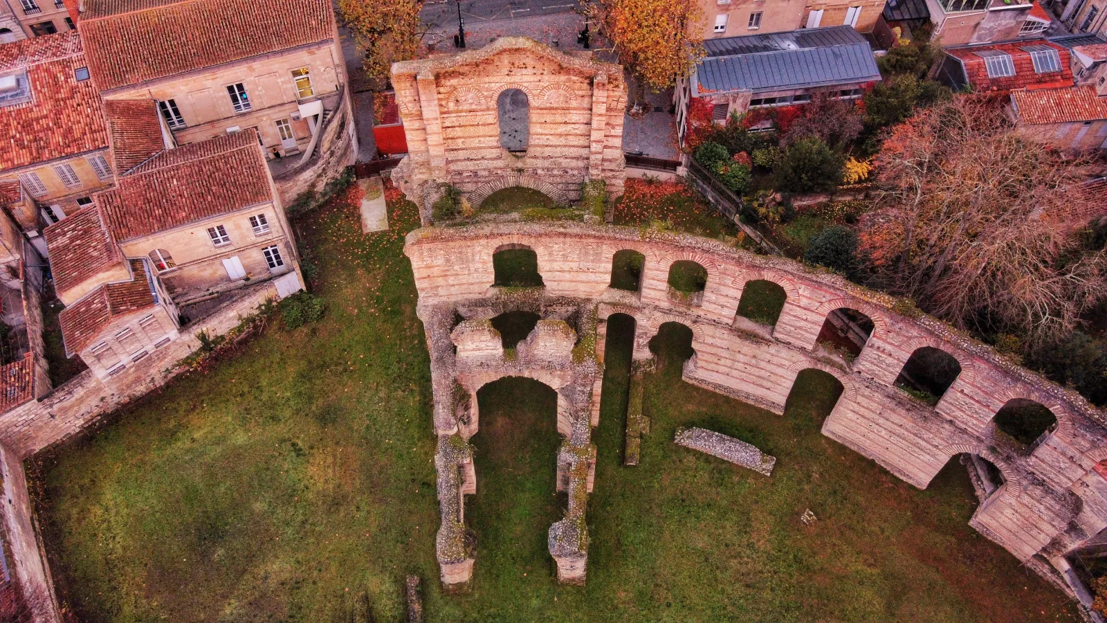 Aerial view of Palais Gallien in Bordeaux, Roman ruins with stone arches surrounded by modern buildings and vegetation