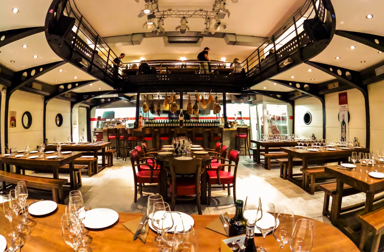 Elegant interior of a Bordeaux brasserie featuring wooden tables, red chairs, a tiered central bar, and Art Deco decor in Bordeaux.